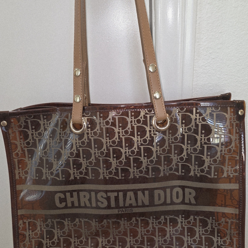 Elegant tote with iconic logo pattern w/ brown handles and transparent body